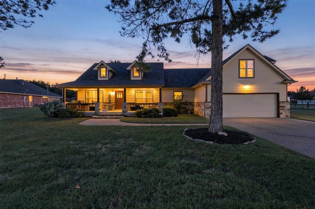 Craftsman-style home with dormer windows, stone accents, a covered front porch, and an attached two-car garage