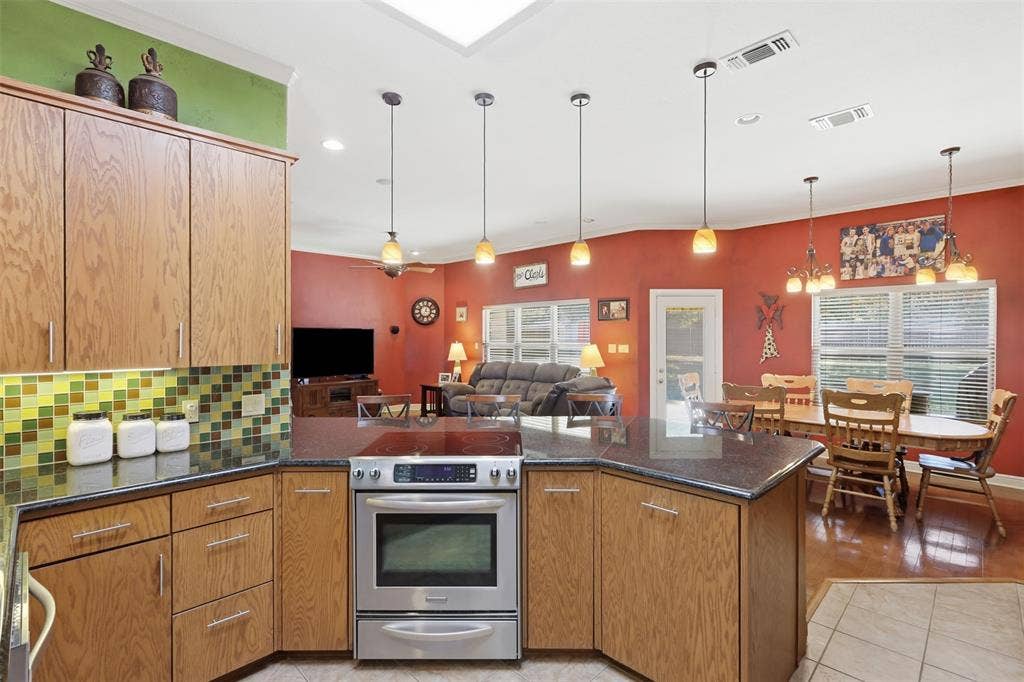 Kitchen island with integrated stainless steel range, dark countertop, and warm wood cabinetry