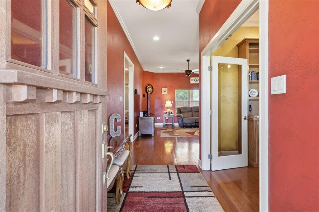 Foyer featuring a wood-panel entry door with transom window, rich wood-finish flooring, and white trim