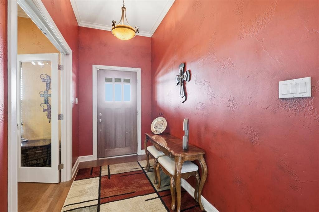Vaulted entryway with wood-finish flooring, decorative ceiling light fixture, and wood-paneled door with glass inserts