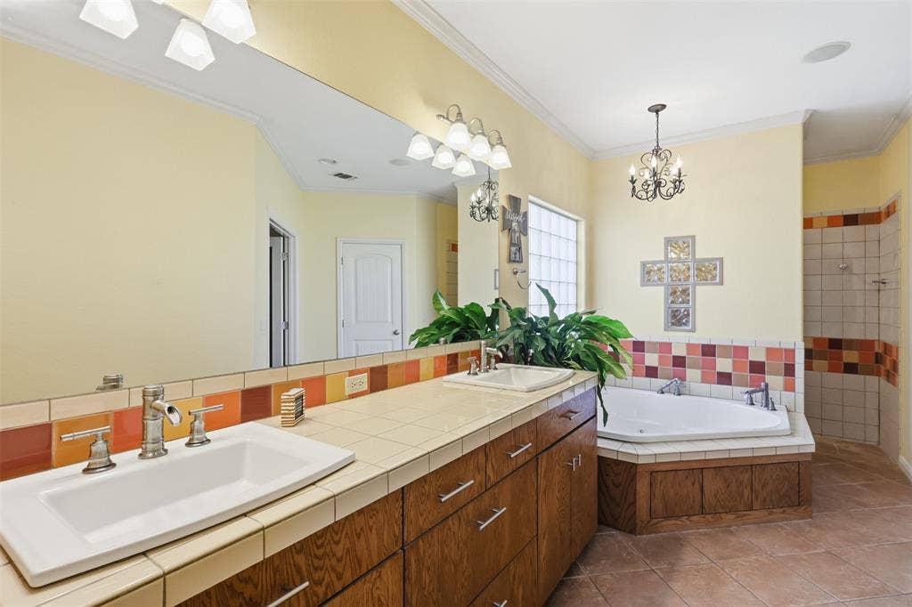 Dual vanity with wood-finish cabinetry, tile countertop, and rectangular undermount sinks
