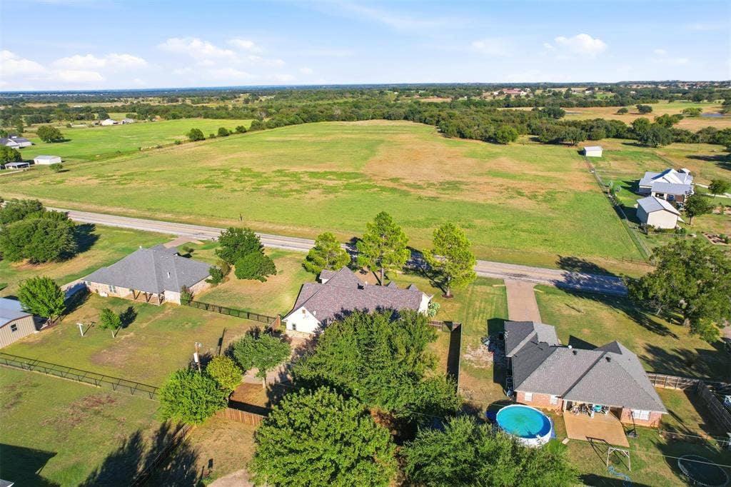 Expansive property featuring a large green field, multiple residential structures, and mature trees