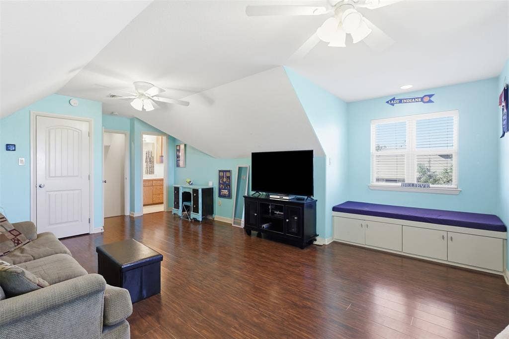 Wood-finish flooring throughout, ceiling fans, built-in window bench with storage, and a white paneled door