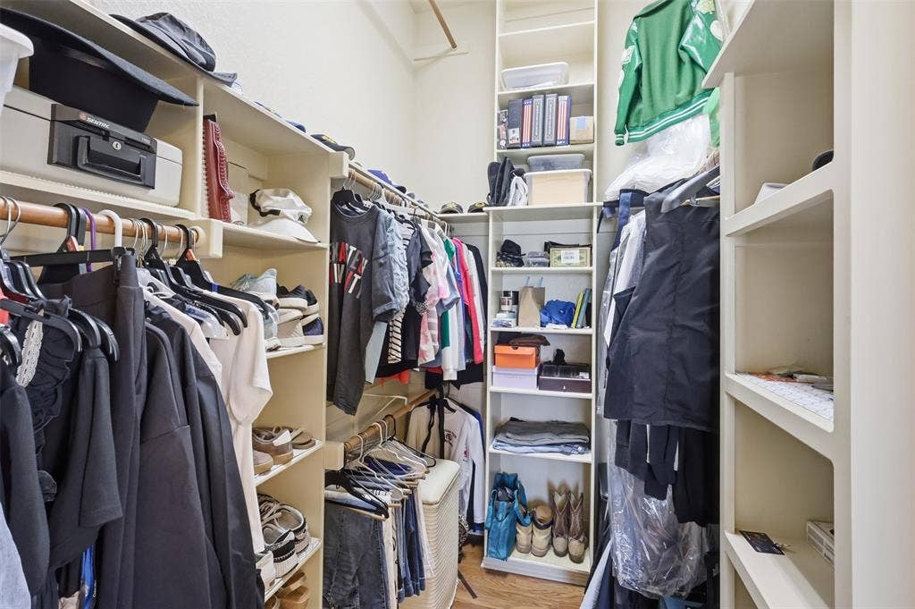 Built-in shelving, multiple hanging rods, and wood-finish flooring