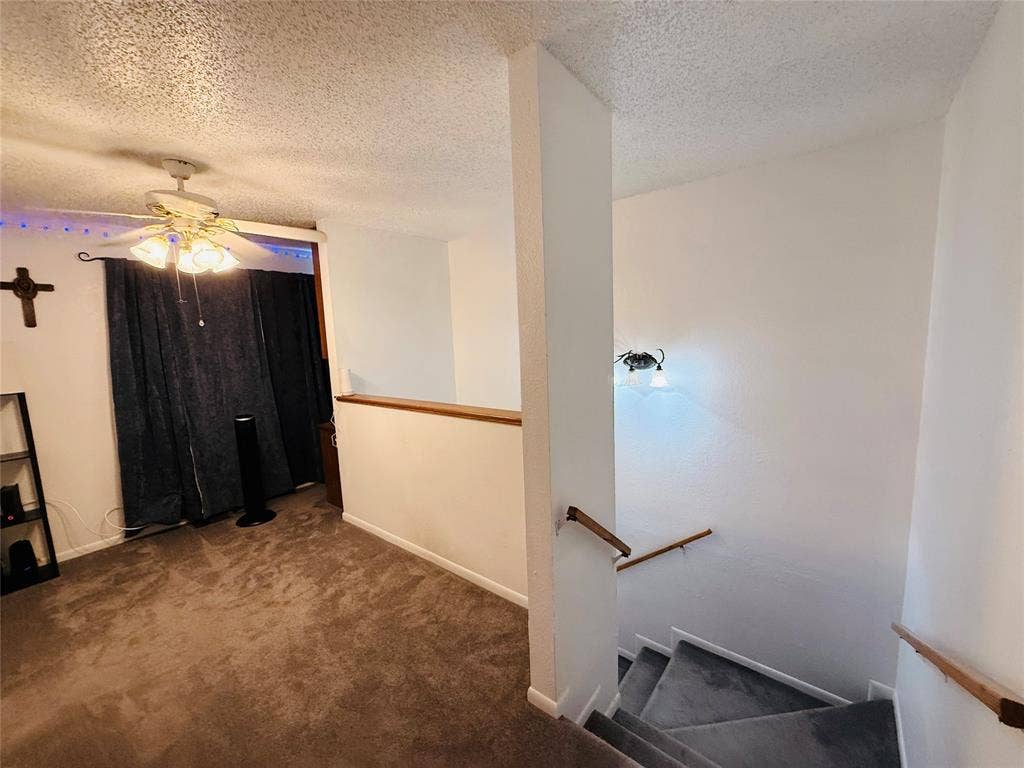 1915 S 10th Street, Waco, TX 76706 Carpeted flooring, ceiling fan with light fixture, wall-mounted light fixture, wood handrails, and a half-wall partition
