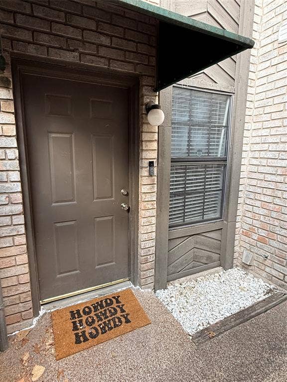 1915 S 10th Street, Waco, TX 76706 Brick exterior with a brown entry door, an exterior light fixture, and an awning over the window