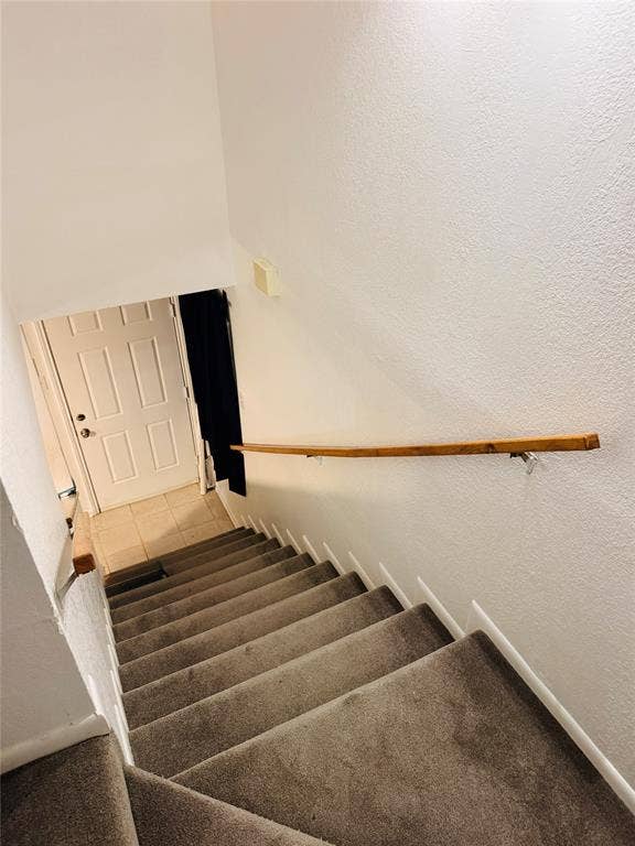 1915 S 10th Street, Waco, TX 76706 Carpeted staircase with a wood handrail, leading to a tiled landing and paneled door