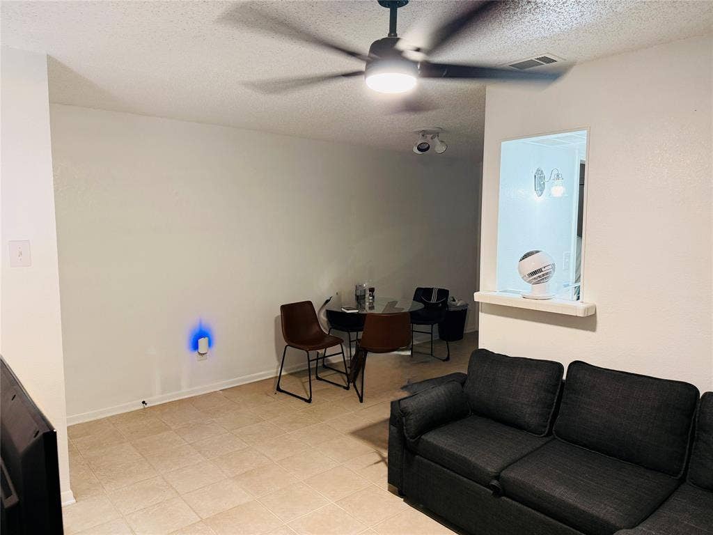 1915 S 10th Street, Waco, TX 76706 Neutral-toned tile flooring, ceiling fan with integrated lighting, and a pass-through opening with a ledge