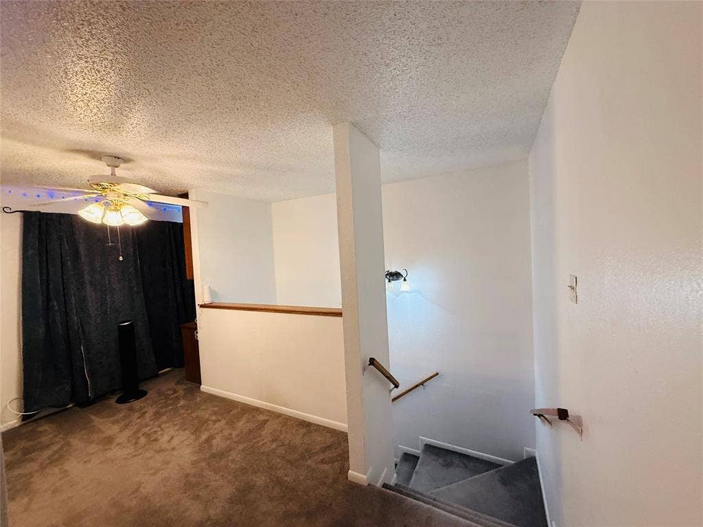1915 S 10th Street, Waco, TX 76706 Carpeted flooring, ceiling fan with integrated lighting, textured ceiling, and wood-finish railing