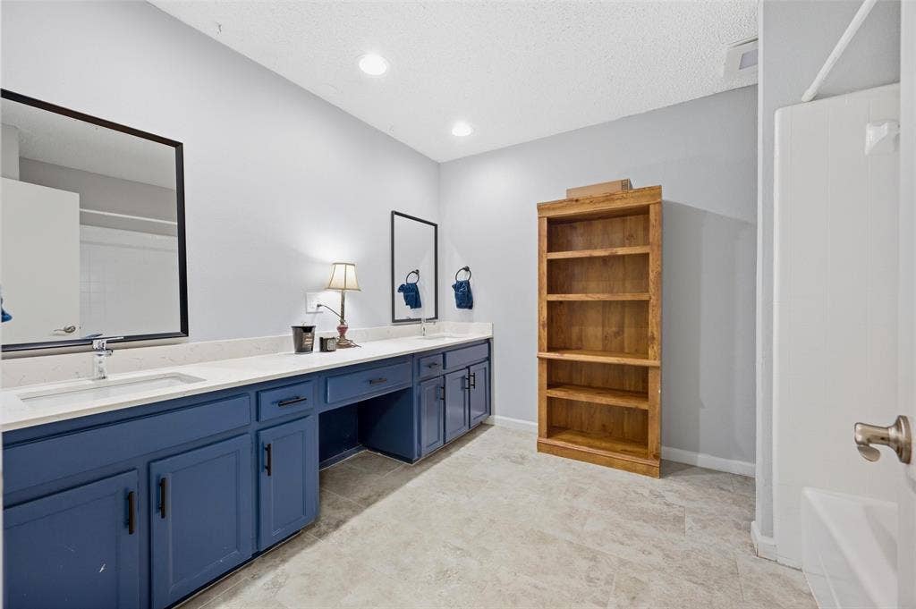 Double vanity with blue cabinetry, white countertops, built-in storage, and two framed mirrors