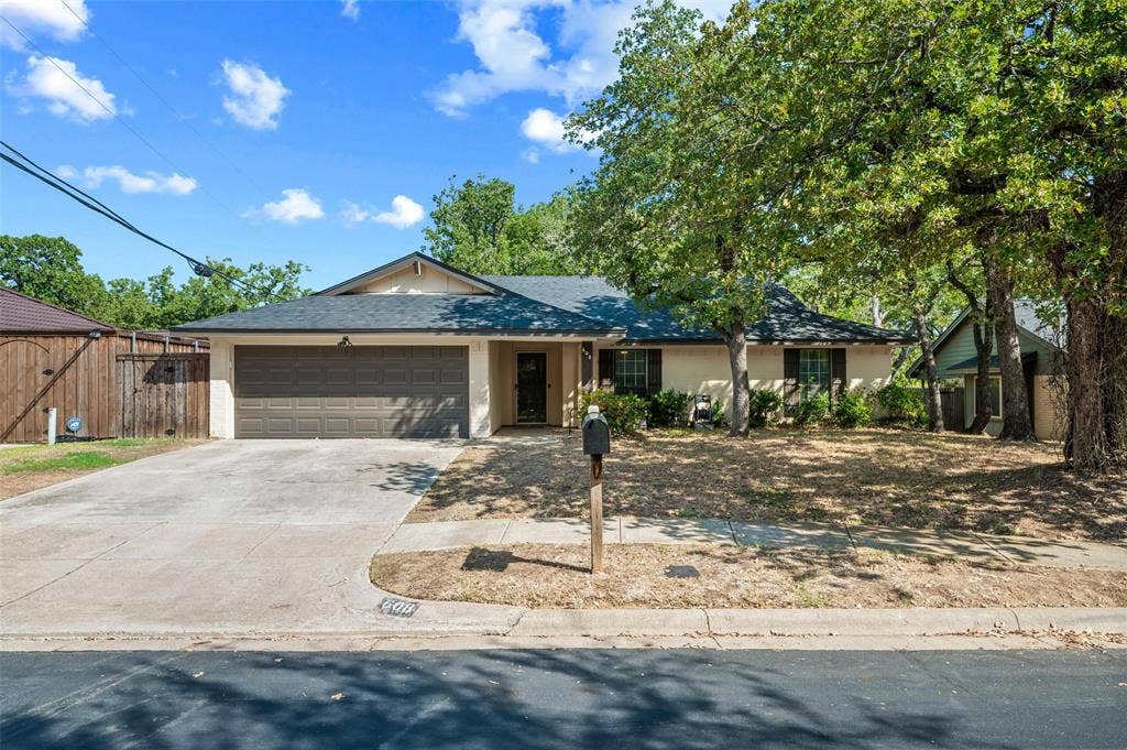 Single-story residence featuring a two-car garage, front yard landscaping, and mature trees