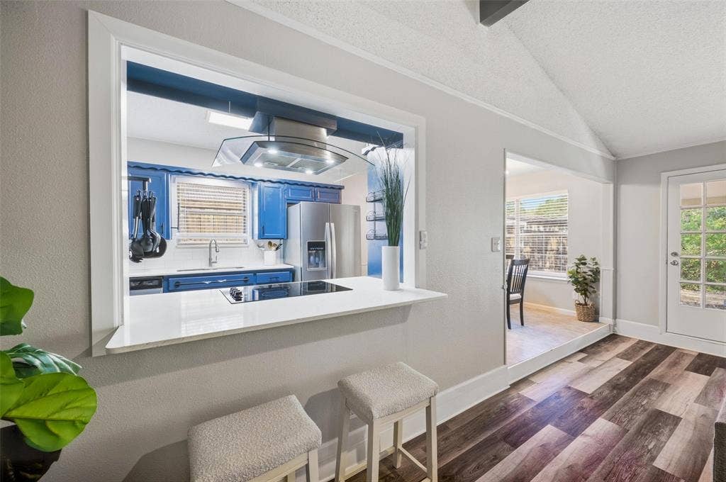 Pass-through window with seating, wood-finish flooring, glass-paneled exterior door, modern kitchen appliances, and recessed lighting