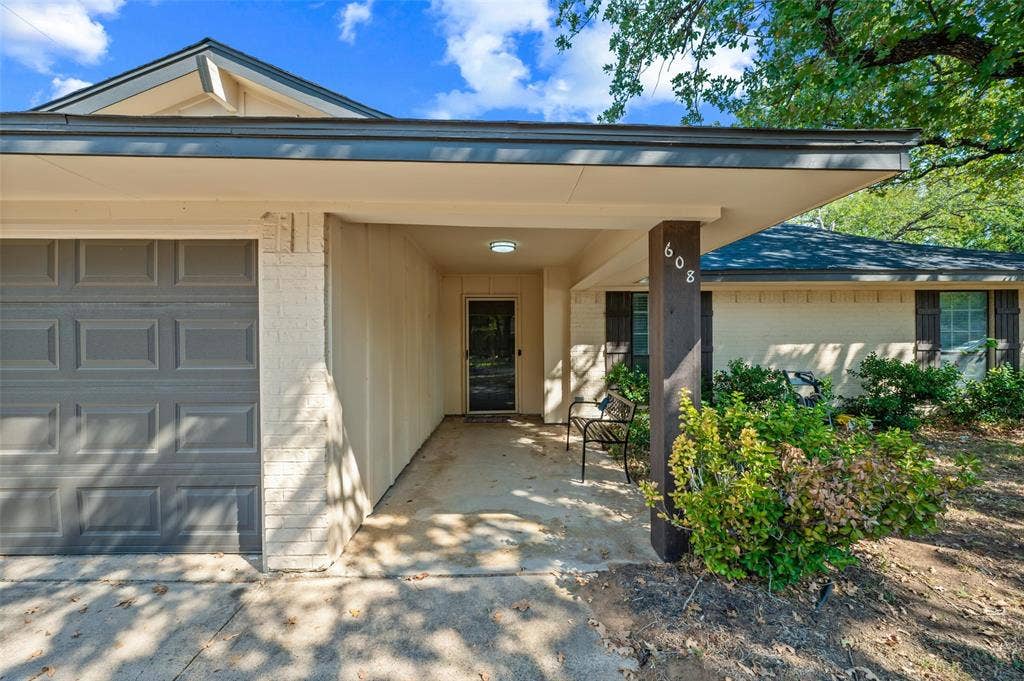 Covered entryway with recessed lighting, integrated garage, and a brick and siding exterior