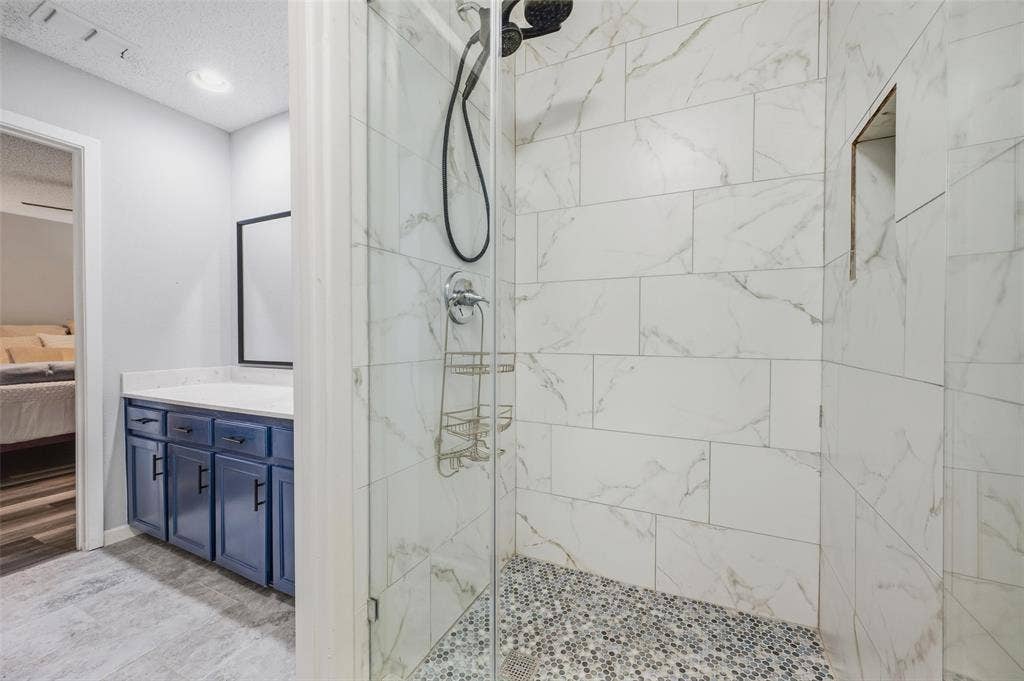 Walk-in shower with clear glass enclosure and mosaic tile floor