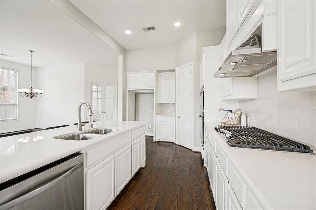 White kitchen light and bright with stainless appliances and gas cooktop