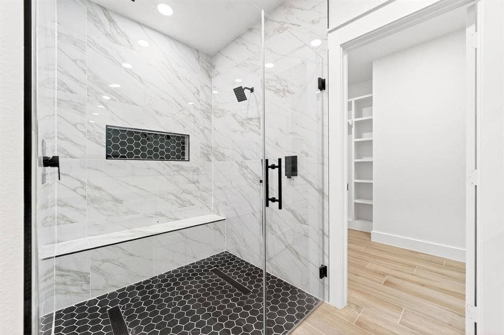 120 Springwood Road, Enchanted Oaks, TX 75156 Glass-enclosed shower featuring white marble-finish tiling, matte black fixtures, a built-in bench, and a hexagonal tiled floor
