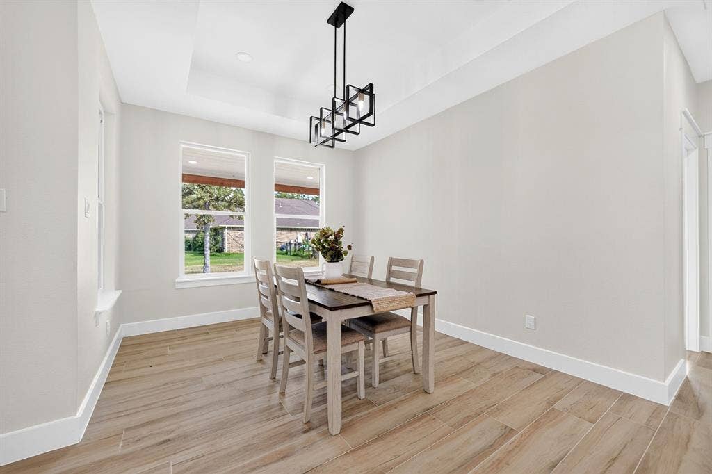 120 Springwood Road, Enchanted Oaks, TX 75156 Tray ceiling with a contemporary black linear chandelier, wood-finish flooring, and multiple windows