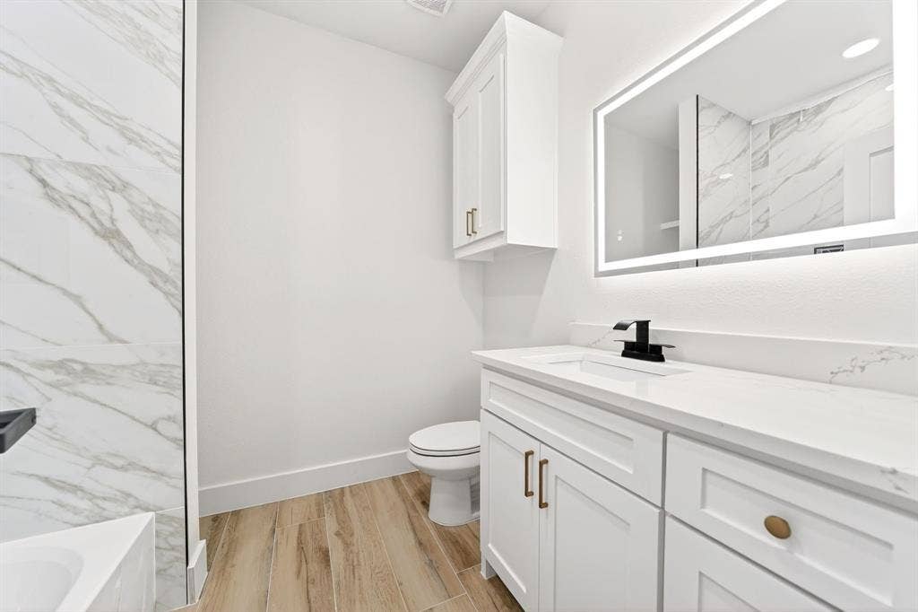 120 Springwood Road, Enchanted Oaks, TX 75156 White vanity with a solid surface countertop, matte black faucet, and an illuminated mirror