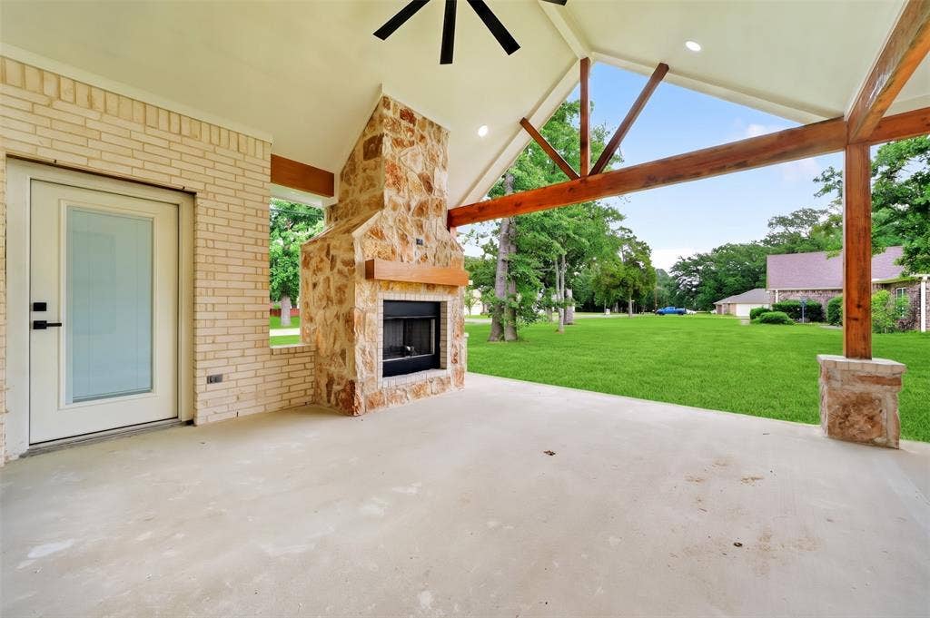 120 Springwood Road, Enchanted Oaks, TX 75156 Covered patio featuring an outdoor fireplace with stone surround, wood mantel, and concrete flooring