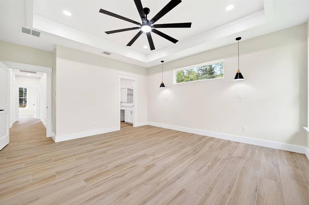 120 Springwood Road, Enchanted Oaks, TX 75156 Spacious room featuring wood-finish flooring, a tray ceiling with a ceiling fan, recessed lighting, and two pendant lights