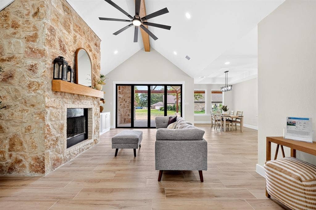 120 Springwood Road, Enchanted Oaks, TX 75156 Vaulted ceiling with exposed beam, stone fireplace with wood mantel, wood-finish flooring, black-framed sliding glass doors, and recessed lighting