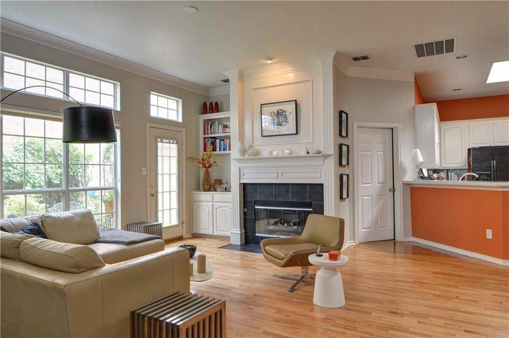8626 Forest Glen Drive, Irving, TX 75063 Hardwood flooring, large windows with transom lighting, built-in shelving, a fireplace with a tile surround, and a kitchen pass-through