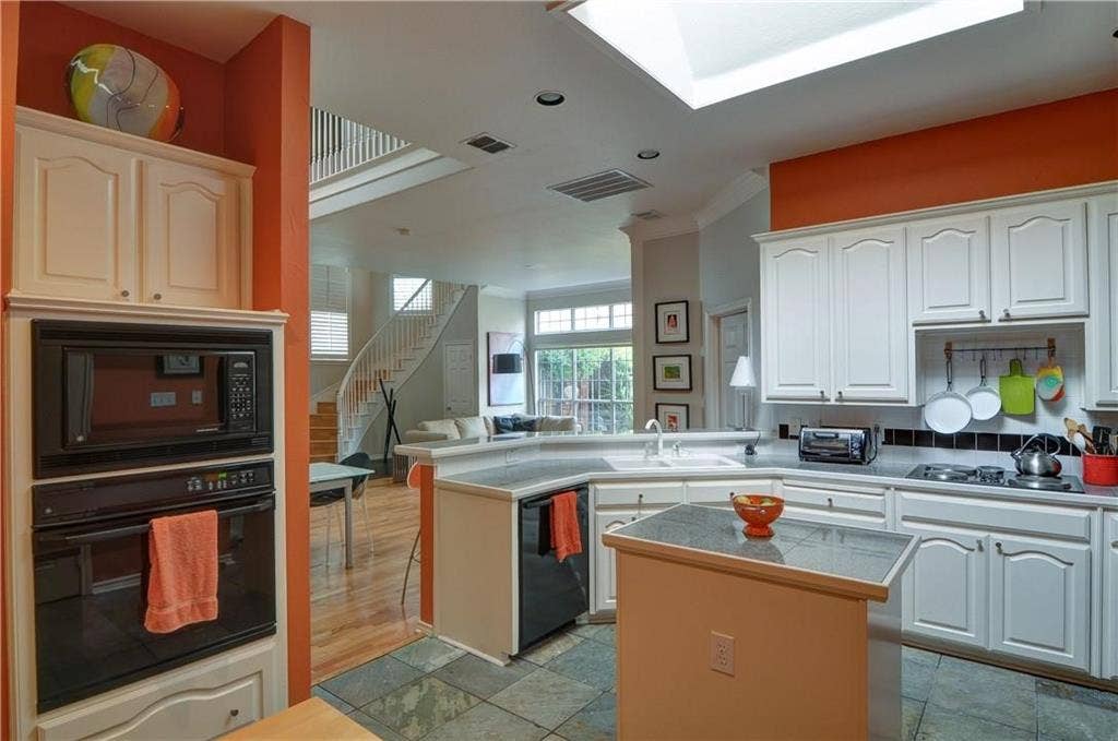 8626 Forest Glen Drive, Irving, TX 75063 Kitchen featuring white cabinetry, built-in wall oven and microwave, skylight, and stone-finish flooring