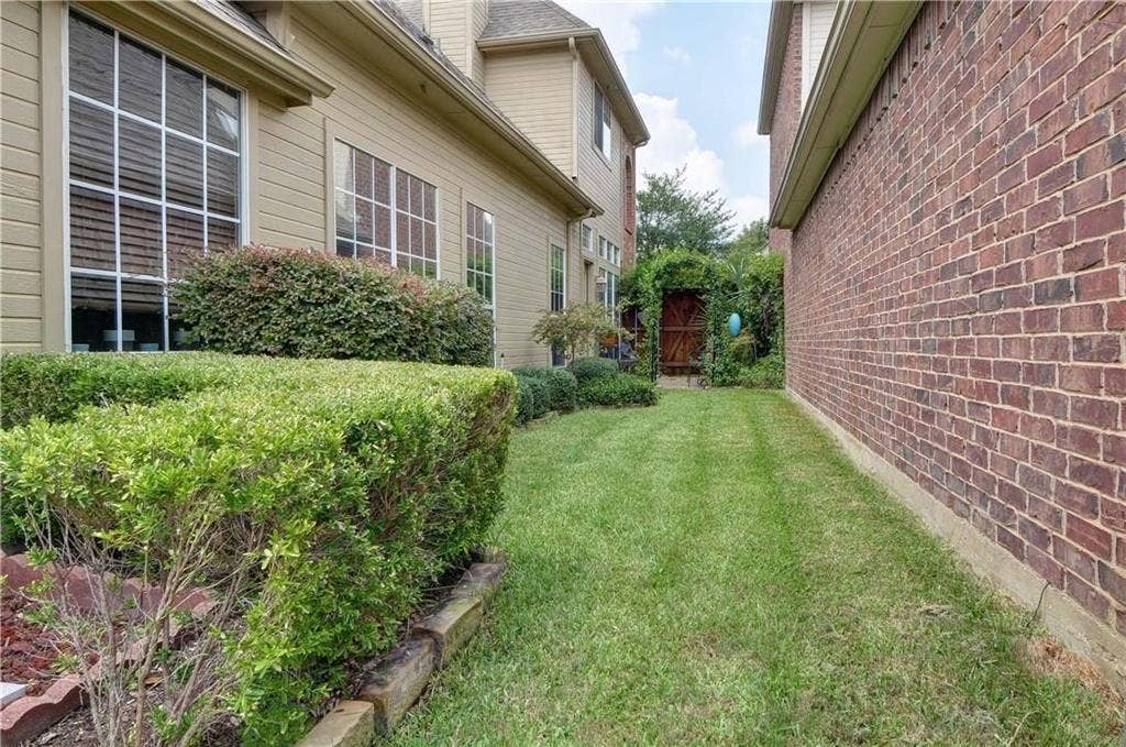 8626 Forest Glen Drive, Irving, TX 75063 Side yard with a manicured lawn, established shrubbery, and a decorative garden gate