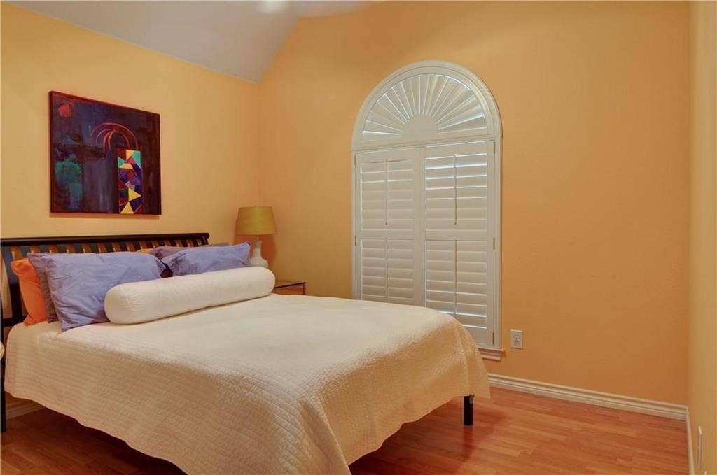 8626 Forest Glen Drive, Irving, TX 75063 Arched window with plantation shutters, wood-finish flooring, and a vaulted ceiling