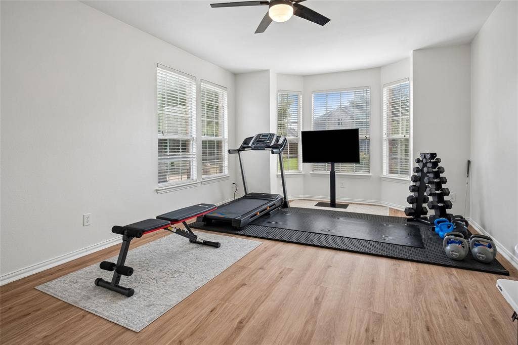 3801 Kite Meadow Drive, Plano, TX 75074 Bay window with multiple window panes, wood-finish flooring, ceiling fan with integrated lighting, and neutral wall tones