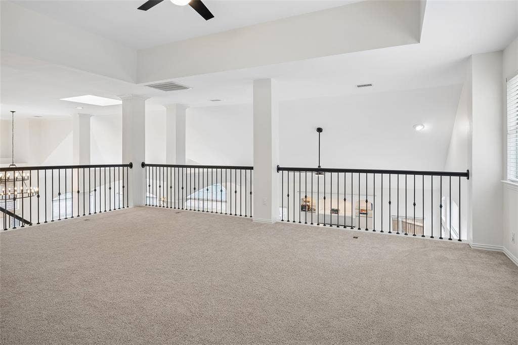3801 Kite Meadow Drive, Plano, TX 75074 Expansive carpeted loft with an open concept design, featuring a contemporary ceiling fan, skylight, and white window blinds