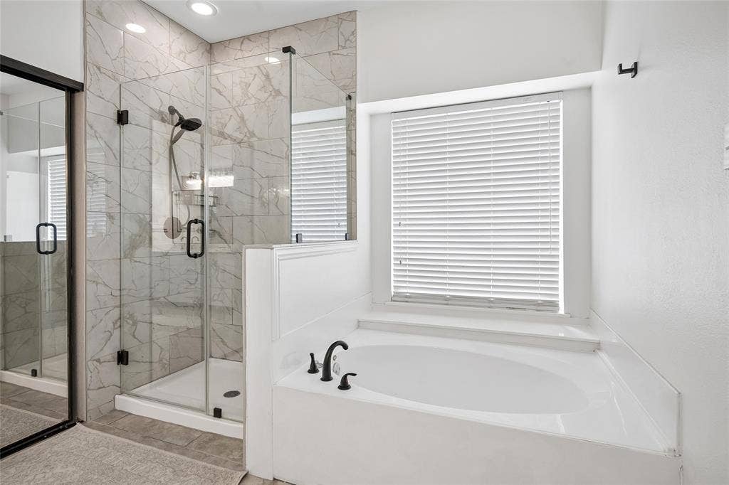 3801 Kite Meadow Drive, Plano, TX 75074 Glass-enclosed shower with tiled walls, separate soaking tub, and matte black plumbing fixtures