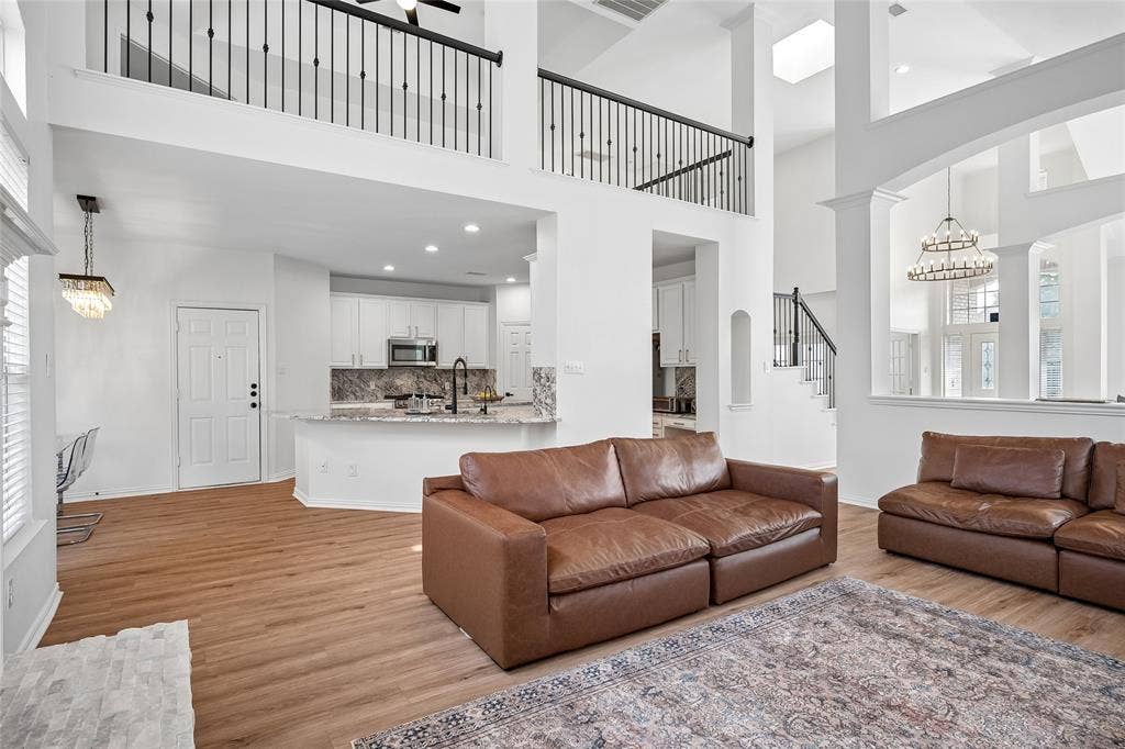 3801 Kite Meadow Drive, Plano, TX 75074 Spacious living area with wood-finish flooring, high ceilings, and a second-story balcony with iron railings
