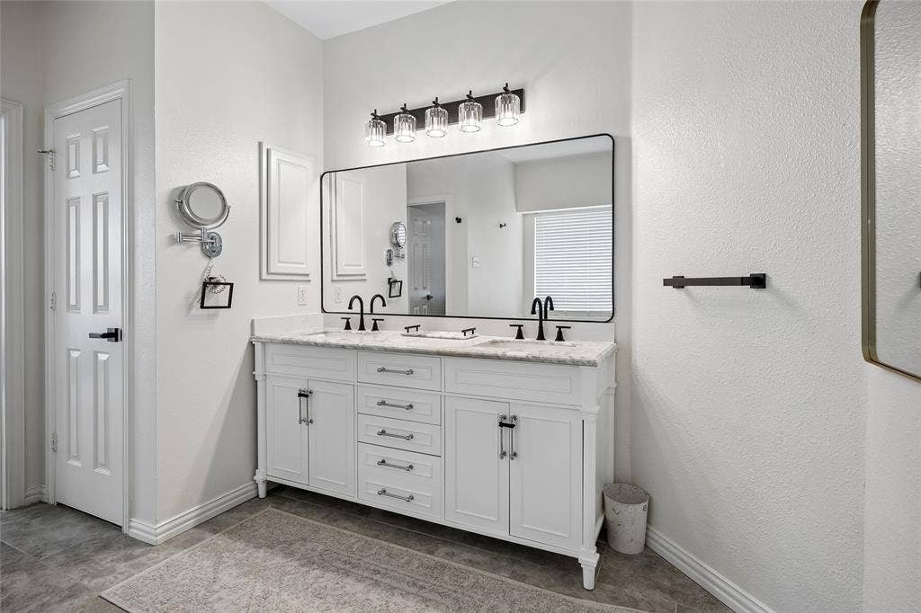 3801 Kite Meadow Drive, Plano, TX 75074 Dual vanity with white cabinetry, stone countertop, matte black fixtures, and a large framed mirror