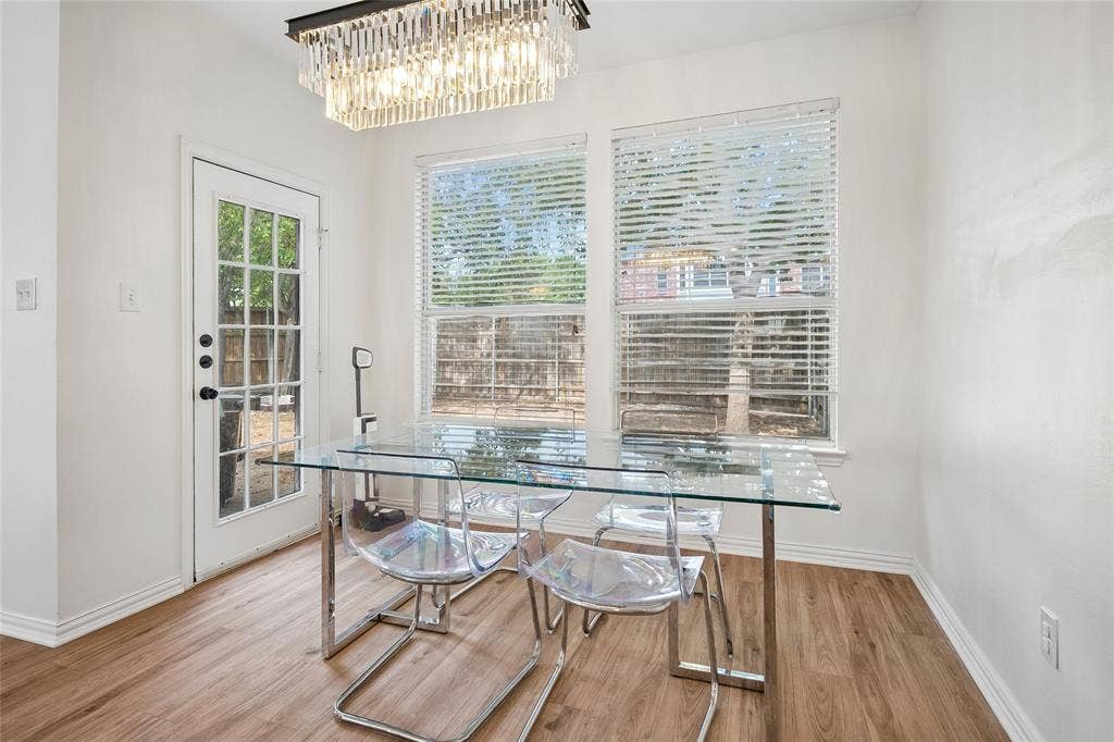 3801 Kite Meadow Drive, Plano, TX 75074 Recessed windows with blinds, a full-lite exterior door, wood-finish flooring, a contemporary crystal chandelier, and white wall finishes