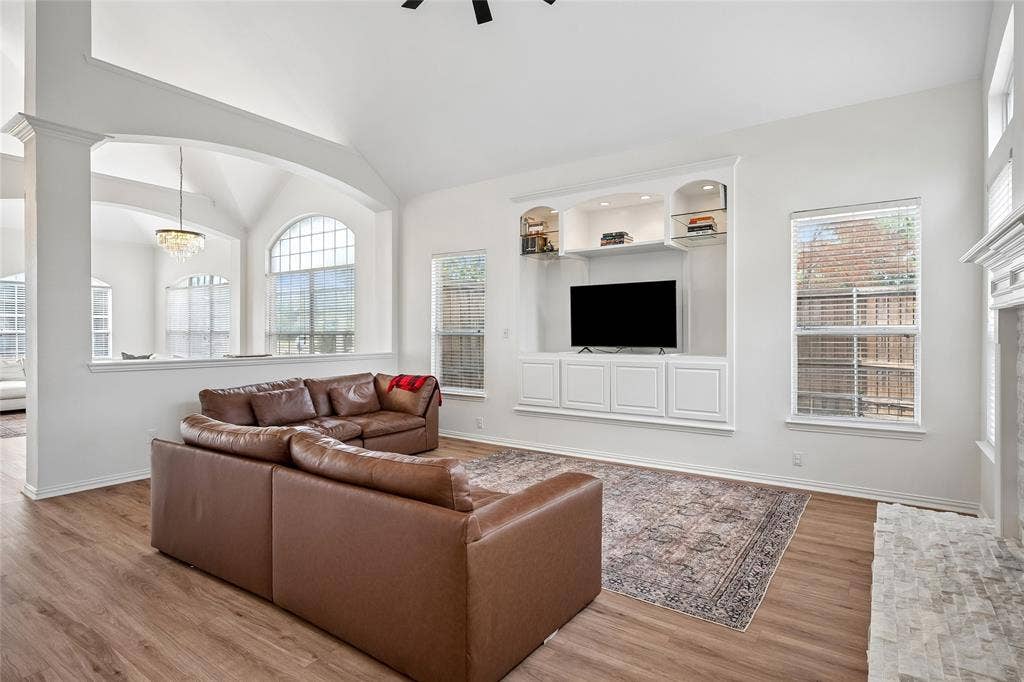 3801 Kite Meadow Drive, Plano, TX 75074 Vaulted ceiling, wood-finish flooring, built-in cabinetry with integrated shelving, archway, and an arched window