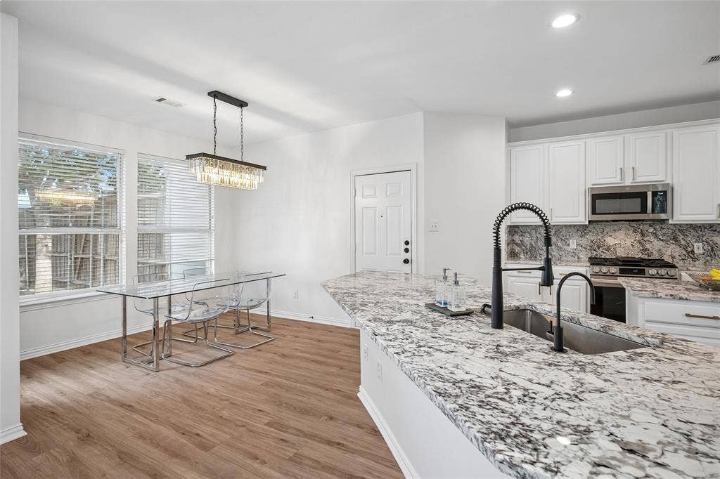 3801 Kite Meadow Drive, Plano, TX 75074 Kitchen featuring white cabinetry, granite countertops, stainless steel appliances, and wood-finish flooring
