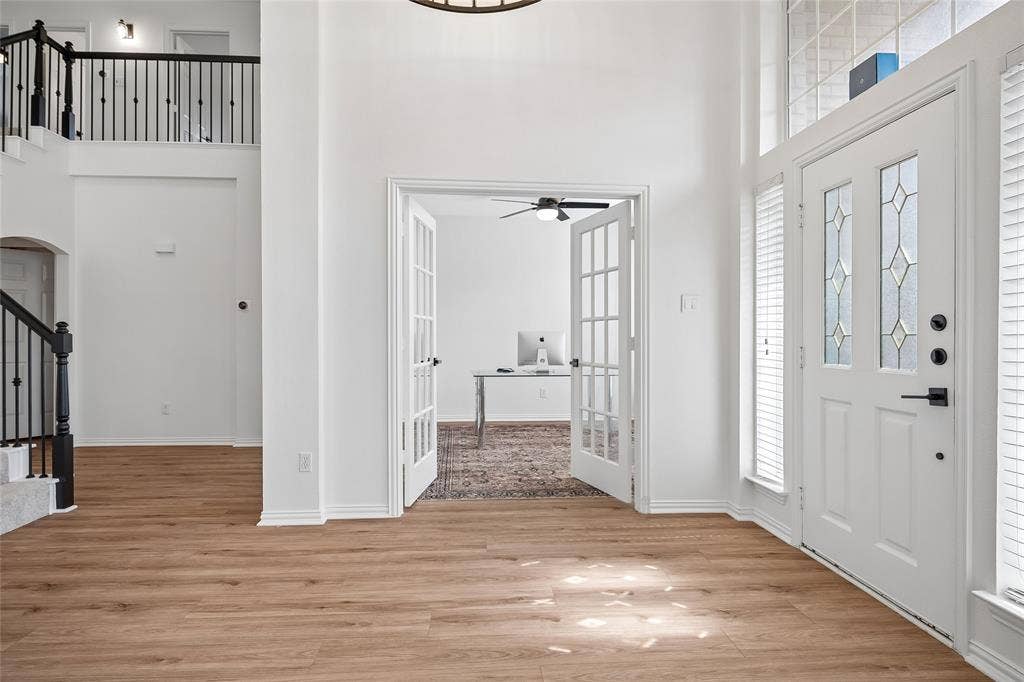 3801 Kite Meadow Drive, Plano, TX 75074 Entryway featuring a decorative glass paneled door, wood-finish flooring, and a two-story foyer