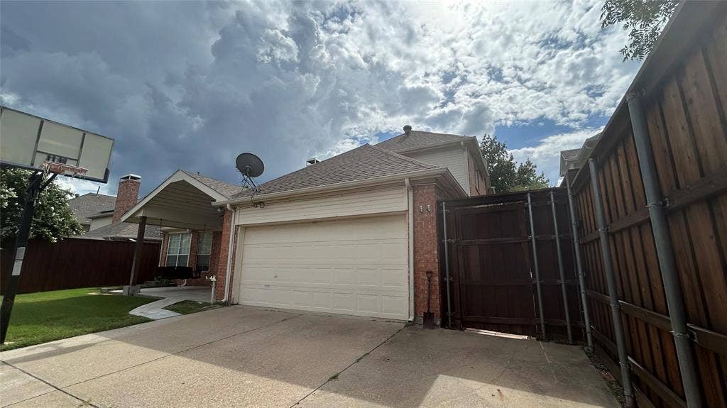 Attached two-car garage with a paved driveway, brick facade, and a covered entryway