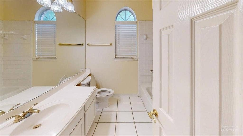 Bathroom with white tile flooring, arched windows, and a vanity with an integrated sink