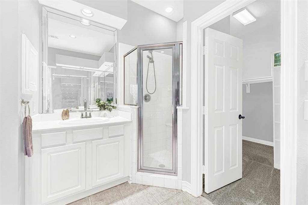 4433 Creekbend Circle, Richardson, TX 75082 Primary bathroom offers separate vanities, a walk-in shower, and a large walk-in closet