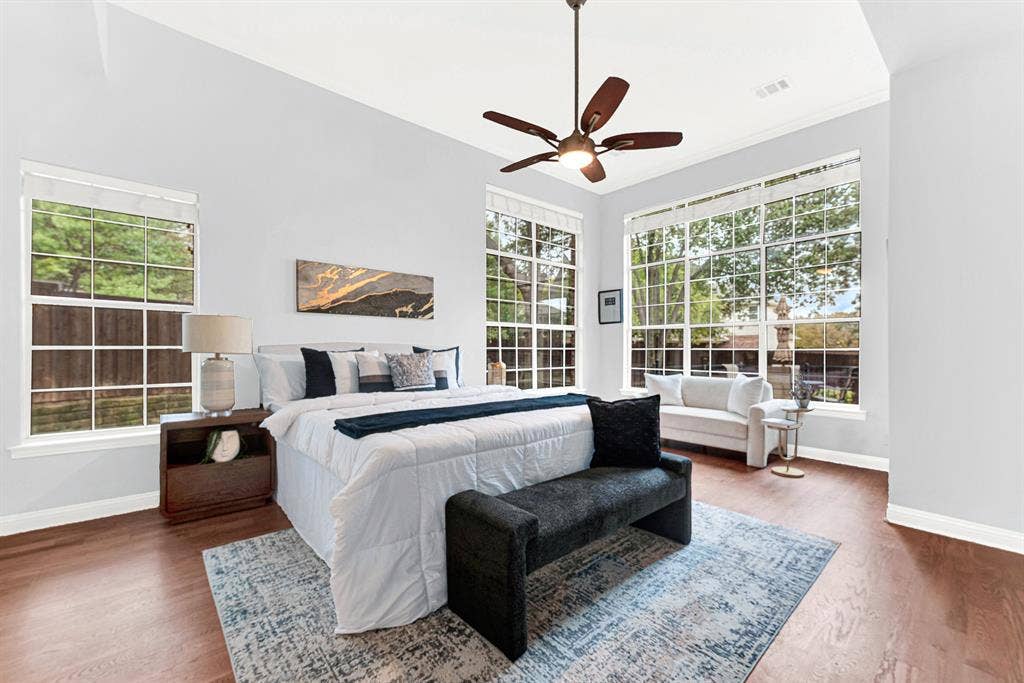 Spacious primary bedroom [on 1st floor] features tall ceiling and wall of windows to the pretty backyard