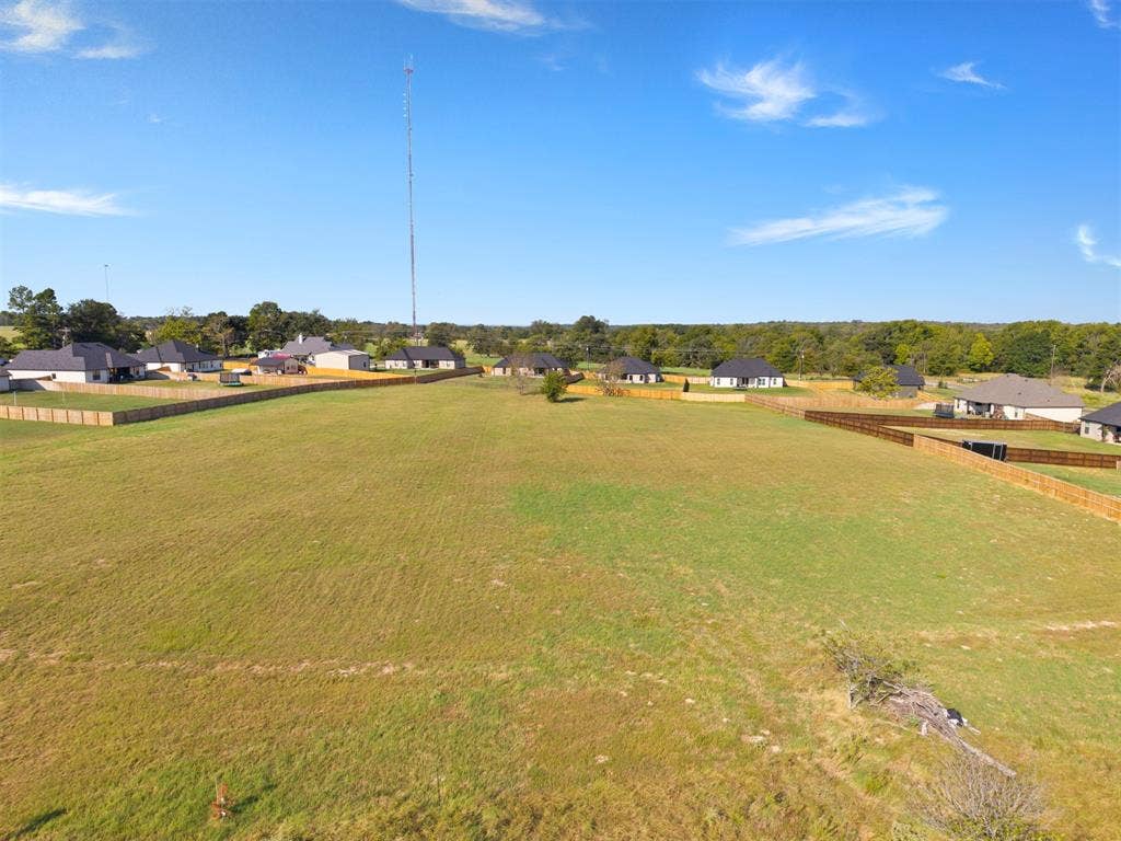 15610 County Road 436, Lindale, TX 75771 Expansive grassy terrain with perimeter fencing and a clear blue sky overhead