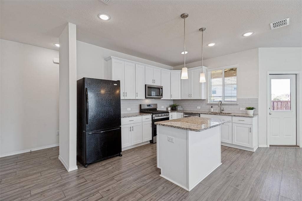 Kitchen equipped with 42" cabinets, granite countertops, gas stove, decorative tile backsplash and pendant lights