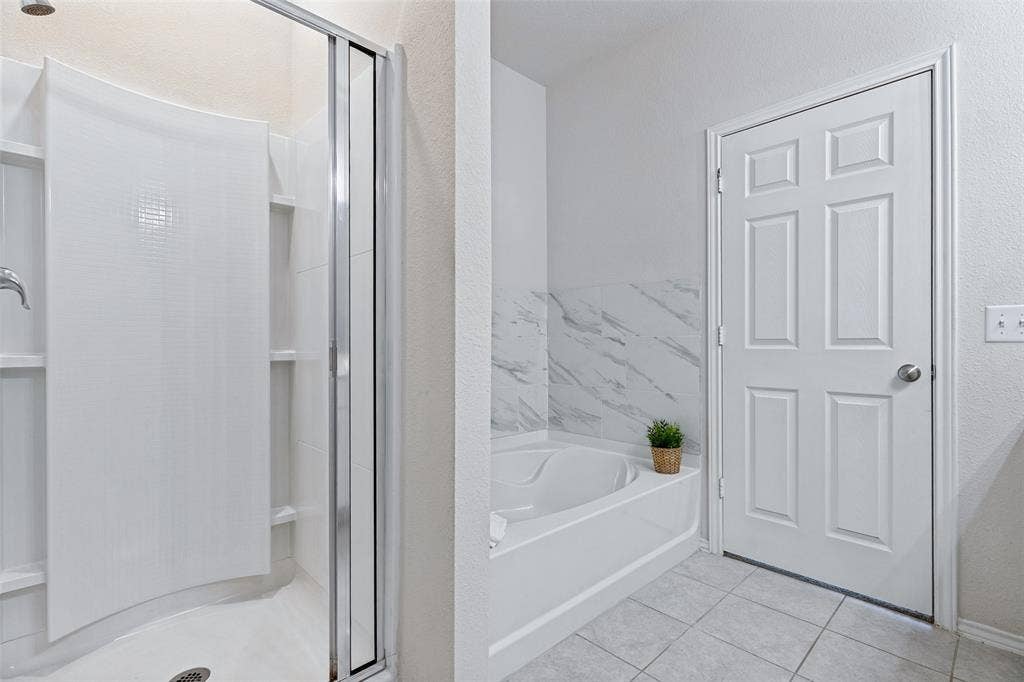 Another view of master bathroom with walk-in shower and separate soaking tub with decorative tile surround