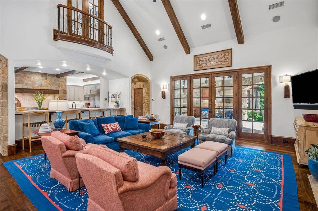 5222 Stonegate Road, Dallas, TX 75209 Vaulted ceiling with exposed wood beams, wood-finish flooring, a Juliet balcony with wrought iron railing, and wood-framed French doors