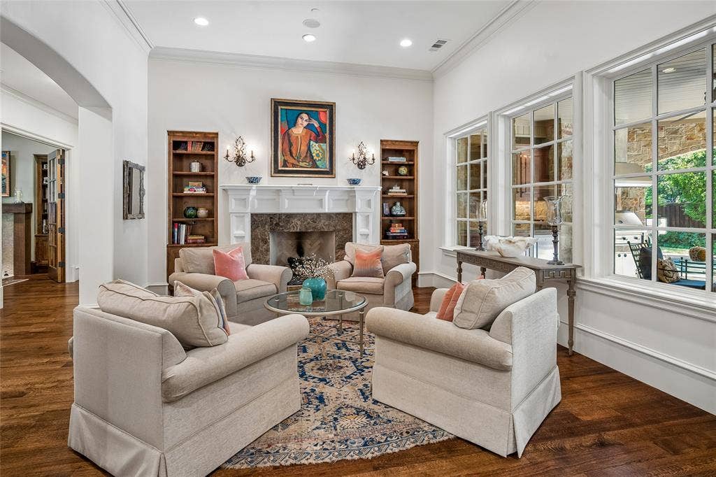 5222 Stonegate Road, Dallas, TX 75209 Hardwood flooring, white crown molding, built-in shelving, fireplace with stone surround and white mantel, large grid-pattern windows