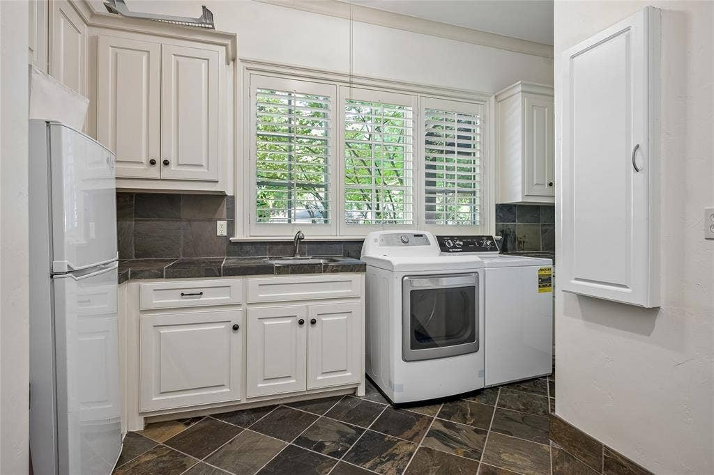 5222 Stonegate Road, Dallas, TX 75209 White cabinetry, dark stone tile flooring, dark backsplash, and plantation shutters
