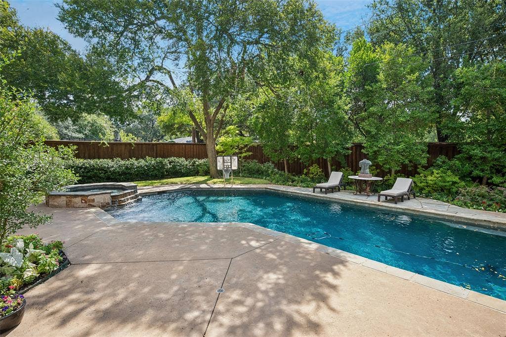 5222 Stonegate Road, Dallas, TX 75209 Expansive backyard featuring a rectangular swimming pool, stone-clad spa with waterfall, concrete patio, and privacy fencing