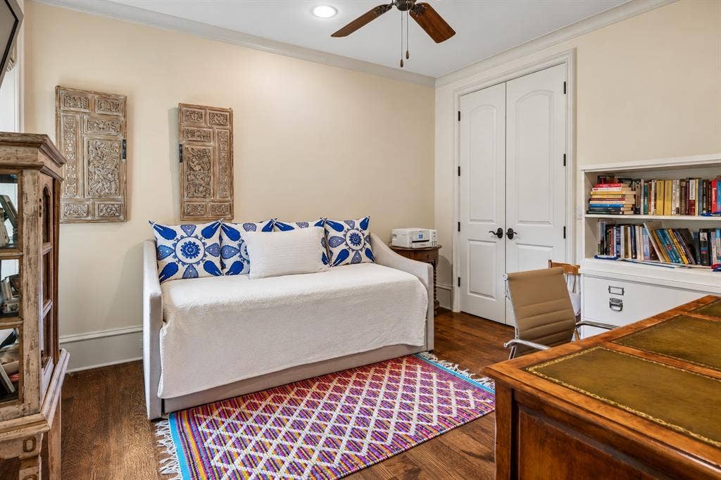 5222 Stonegate Road, Dallas, TX 75209 First floor guest bedroom suite. Wood-finish flooring, built-in shelving, white paneled doors, and a ceiling fan
